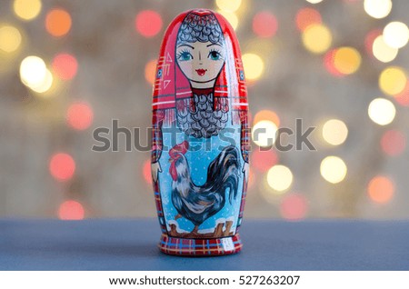 The picture on the doll matryoshka. Rooster - a symbol of the New year. Blurred background