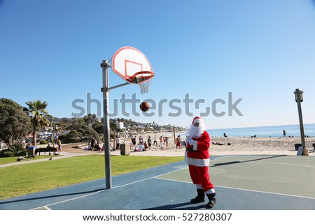 Santa Claus plays Basket Ball outside. Santa shoots and scores while playing basket ball.