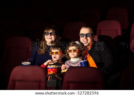 Cinema day, happy family with popcorn and drinks looking interesting film in cinema