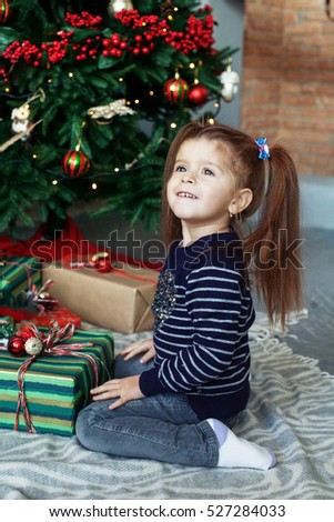 Happy little girl opening gifts. The concept of Christmas and New Year.