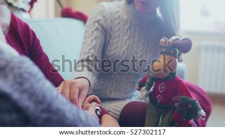 Son sits on his father's knee. Mom playing with baby. Christmas toy - Christmas deer, assistant Santa, reindeer Rudoflf. Family is ready for Christmas. Christmas family.