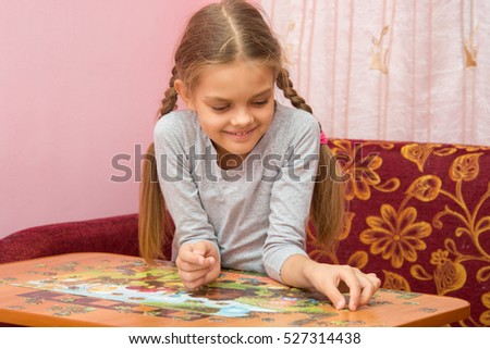 Girl collects a picture from puzzles
