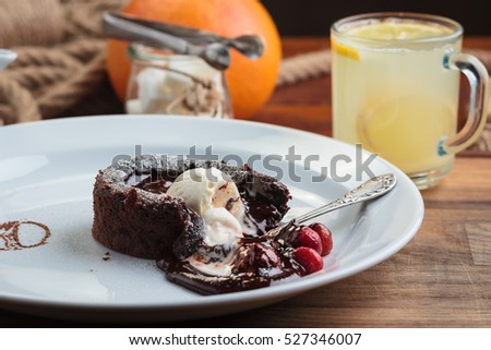 Concept: restaurant menus, healthy eating, homemade, gourmands, gluttony. White plate with chocolate fondant with strawberry and ice cream on a messy vintage wooden background.