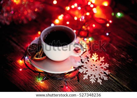 Cup of coffee with cinnamon and lemon on a Christmas light background.