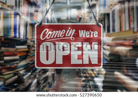 A business sign that says 'Come in We're Open' on a book store window.