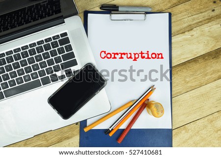 Corruption word in notepad with wooden background, texture and notebookin a table. 