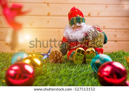 Santa claus doll in Christmas day on green grass and wood background. Morning sunshine day and good day.