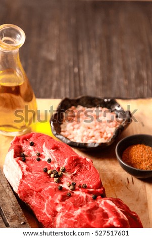 piece of raw meat with hand weights on the old wooden background