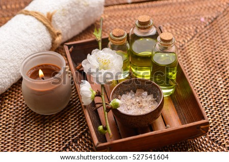 Tropical setting on mat with massage oil,candle,cherry,towel Royalty-Free Stock Photo #527541604
