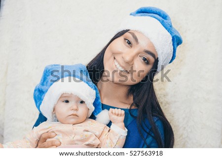 woman of Asian appearance in blue Christmas cap plays with a garland and gift