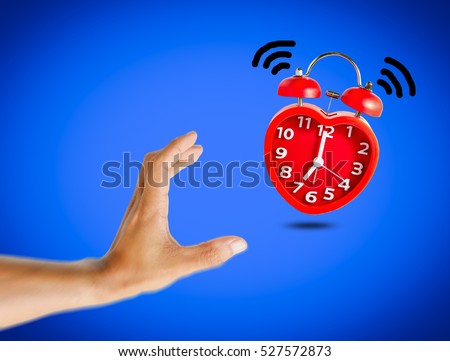 Red bell alarm clock wake up at 7 o'clock with human hand try to stop it.