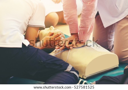 CPR training medical procedure - Demonstrating chest compressions on CPR doll in the class