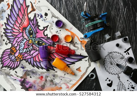Tattoo machine, sketch and supplies on table