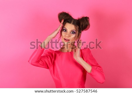 Beautiful and stylish brunette girl in the image of a doll posing on a background of a pink wall