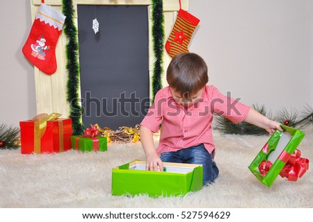 Little boy opening a Christmas present. Kid opening New Year gifts