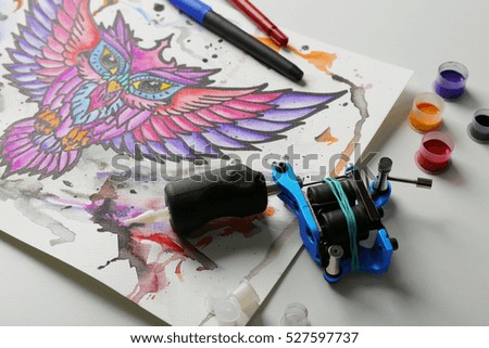 Tattoo machine, sketch and supplies on table