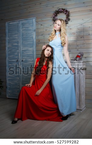 Two young young girls in long gowns in a room with a fireplace