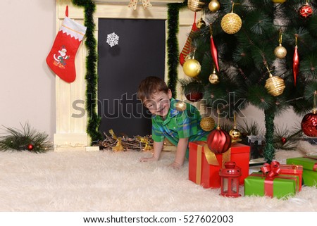 Playful boy tries to steal a gift under the Christmas tree