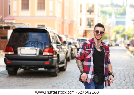 Young tattooed man posing on blurred city street background