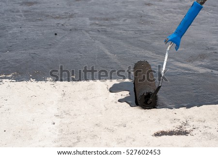 Roofer worker painting black coal tar or bitumen at concrete surface by the roller brush, A waterproofing. Royalty-Free Stock Photo #527602453