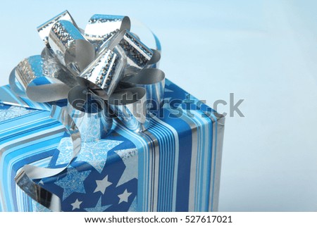 Beautiful gift box with silver ribbon on a blue background.
