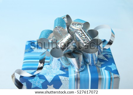 Beautiful gift box with silver ribbon on a blue background.