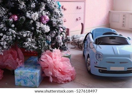 christmas tree with decoration on the pink room background and retro toy car with presents under the tree