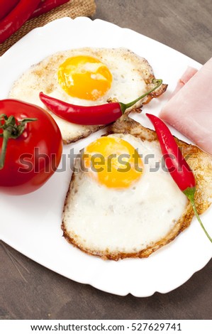 fried egg on a white plate with chili peppers