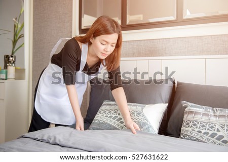 Asian young maid tidying up bed in hotel room, Cleaning service concept