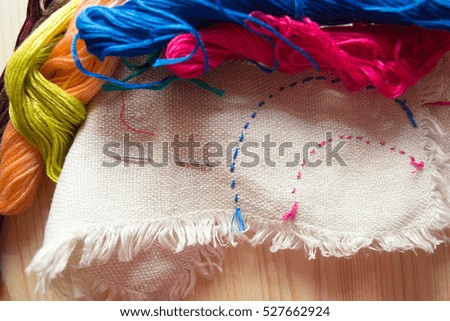 embroidery floss and cotton fabric with embroidery on wooden background. handmade concept. textile manufacturing concept.