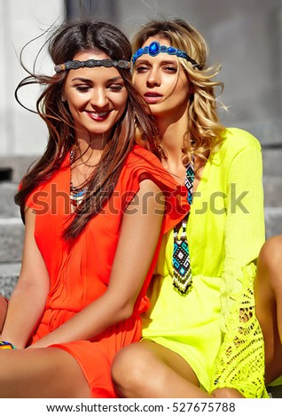 Fashion portrait of two young hippie women models in summer sunny day in bright colorful hipster clothes