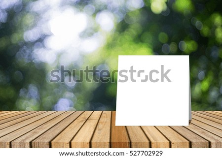white card put on Wooden desk or wooden floor on green bokeh background.use for present or mock up your product.clipping path include