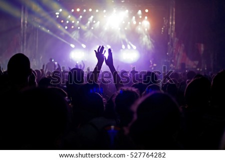 Crowd at popular music concert. Motion blur,
some noise due the use of high ISO because of difficult lighting conditions. 
 Royalty-Free Stock Photo #527764282