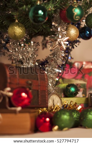 Clock and presents in front of Christmas tree with beautiful ornaments.