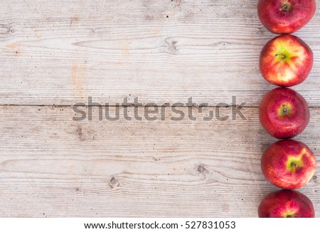 Fresh red apples decorated in a line on wooden background with copy space.