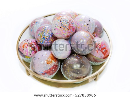 Christmas hand painted chocolate candy balls shades of pink on a vintage plate. Isolated on white. Natural light.
