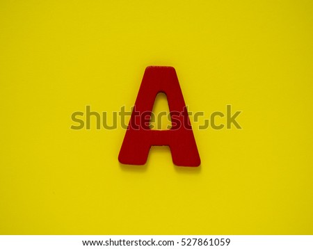 Capital red letter A from wood on yellow background. Alphabet vowel.