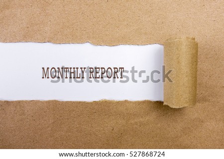 Torn brown paper on white surface with "MONTHLY REPORT" word. Business concept