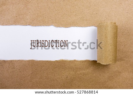 Torn brown paper on white surface with "JURISDICTION" word. Business concept