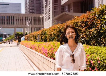 Successful japanese business woman smiling walking along city center.