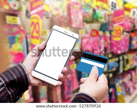 Hand Hold Smart phone with Credit Card over blurred of Shopping mall. blurry backgrounds