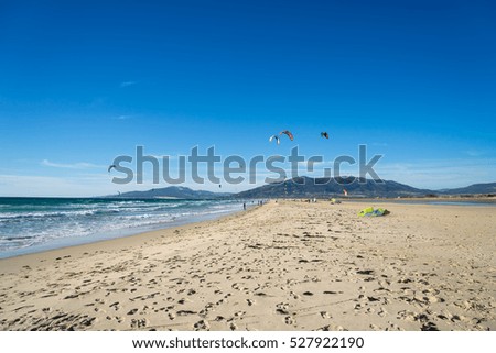Kitesurfing in Tarifa. Plenty of colorful kites flying against a background of the mountains, beautiful clouds and waves of the Atlantic Ocean
