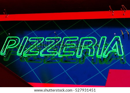 Neon sign on the front of a pizza shop with the word Pizzeria