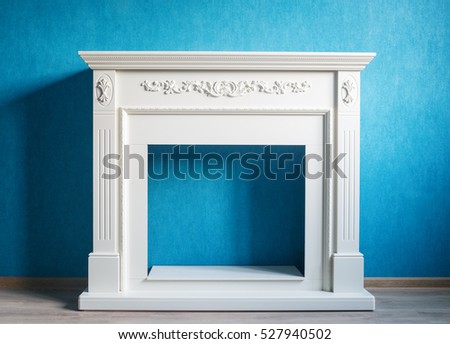 Beige portal for the electric fireplace. The picture was taken in the interior on the background wall of aqua color. The floor is light-colored laminate. Natural light from the window.