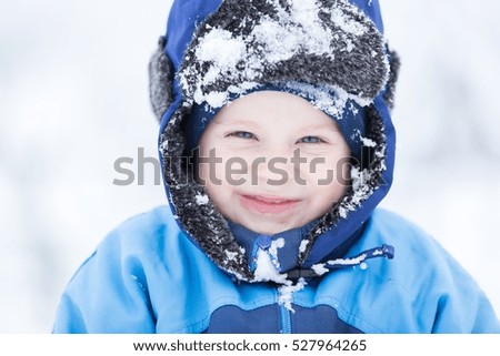 Boy playing in big snow in winter. Happy caucasian child playing in snow.
