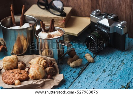 Metal mugs with cacao and marshmallows, with different decorations, soft focus background