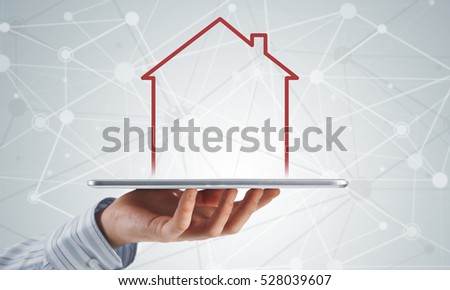 Hand holding modern tablet and house sign on screen