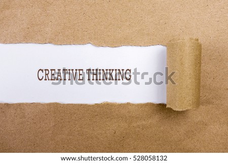 Torn brown paper on white surface with "CREATIVE THINKING" word. Business concept
