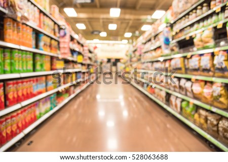 Blurred image of snacks and canned chips aisle in store at Humble, Texas, US. Wide perspective view shelves variety of snacks, defocused blurry background bokeh light in supermarket. Business concept. Royalty-Free Stock Photo #528063688