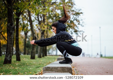 Wman in functional training outdoor at park doing fitness exercise. Sporty girl doing jumps. Royalty-Free Stock Photo #528072109